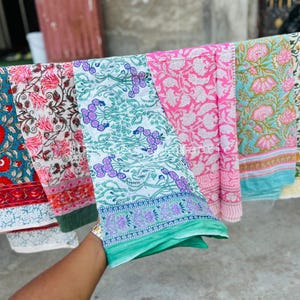 Pu&ograve; includere: Cinque pannelli di tessuto con motivi diversi in vari colori, tra cui rosa, blu, verde e bianco. I pannelli sono appesi a una linea e hanno un design floreale.