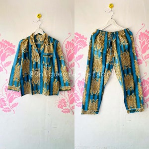 以下が含まれることがあります： 虎柄の青と金の色のパジャマセット。セットには、襟付きの長袖シャツとズボンが含まれています。