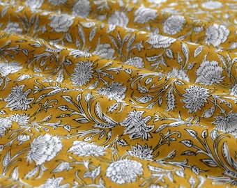 May include: A mustard yellow fabric with a white floral pattern. The fabric has a subtle texture and a soft, flowing drape.