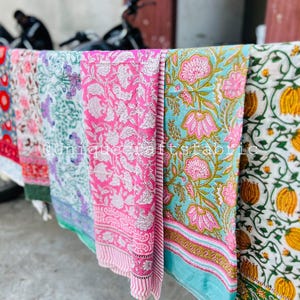 Pu&ograve; includere: Quattro sciarpe di cotone colorate con motivi floreali. Le sciarpe sono appese a uno stendino e sono realizzate in un tessuto morbido e leggero. Le sciarpe sono in tonalit&agrave; di rosa, blu, verde e giallo.