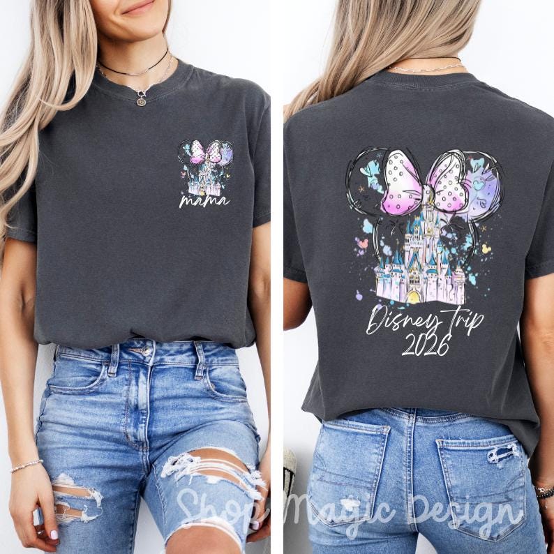 Puede incluir: Camiseta gris oscuro con un dise&ntilde;o tem&aacute;tico de Disney. La parte delantera presenta un peque&ntilde;o gr&aacute;fico con un castillo, un lazo y la palabra "mama". La parte trasera muestra orejas de Mickey Mouse, un castillo, un lazo y el texto "Disney Trip 2026."