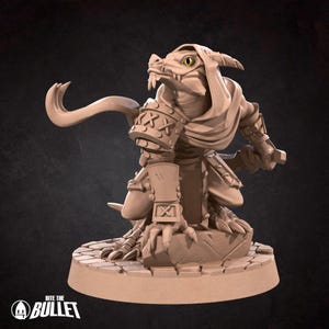 May include: A tan-colored fantasy figurine of a reptilian humanoid warrior, posed with a curved tail and a hooded cloak. The figure is detailed with armor and a sword, standing on a stone base. The base has the text "Bite the Bullet".