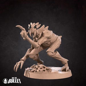 Peut inclure: Figurine miniature beige d'une créature détaillée avec plusieurs yeux, des dents acérées et des mains et pieds griffus. La figurine est posée dans une posture dynamique, un bras tendu, sur une base circulaire. Le texte "Bite the Bullet" est visible.