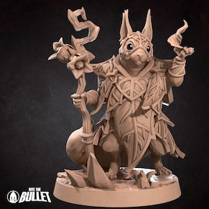 Peut inclure: Une figurine miniature d'un écureuil portant une armure de feuilles et tenant un bâton surmonté d'une fleur. La figurine est peinte en brun clair et se tient sur une base ronde.