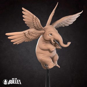 Puede incluir: Una escultura caprichosa de un elefante con alas emplumadas, en color marrón claro. El elefante se representa con una trompa, orejas grandes y una expresión sonriente. La escultura está montada sobre un soporte negro. El texto "BITE THE BULLET" está en la parte inferior.