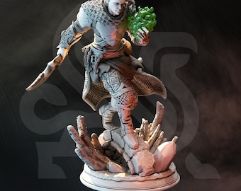 May include: A detailed miniature figurine of a dark elf warrior with a green glowing orb in their hand. The elf is wearing chainmail armor and a patterned robe. The figurine is standing on a rocky base.