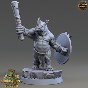 Puede incluir: Una figura miniatura gris y detallada de una criatura similar a un rinoceronte que sostiene un garrote con púas en una mano y un escudo redondo en la otra. La criatura lleva un taparrabos y tiene una complexión musculosa. La miniatura está de pie sobre una base rocosa gris.