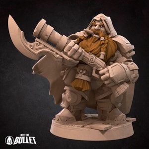 Op de afbeelding: Een miniatuurfiguur van een dwerg-krijger die een capuchonmantel draagt en een grote bijl en een geweer vasthoudt. De dwerg heeft een lange, gevlochten baard en een vastberaden uitdrukking.