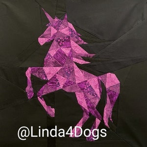 May include: A purple unicorn made of fabric is on a black background. The unicorn is made of many small triangles of fabric. The unicorn is standing on its hind legs with its front legs raised. The unicorn has a horn and a mane. The unicorn is a patchwork of different purple fabrics. The text "@Linda4Dogs" is at the bottom of the image.