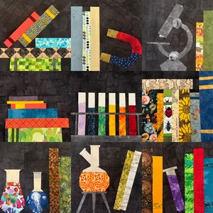 Pu&ograve; includere: Una colorata trapunta patchwork a tema scientifico. La trapunta presenta immagini di beute, provette, un microscopio e il numero 4. I tessuti utilizzati includono vari motivi e colori, come floreali, geometrici e tinte unite.