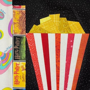 Peut inclure: Un motif de tissu coloré représentant un seau de pop-corn à rayures rouges et blanches, rempli de pop-corn jaune. À côté, des couvertures de livres de la série Harry Potter et un tissu sur le thème du Dr. Seuss. Le fond est noir avec des étoiles blanches.