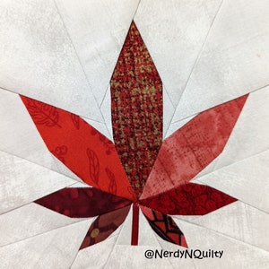May include: A red, gold, and white patchwork quilt block featuring a stylized maple leaf design. The leaf is made up of various fabric scraps in shades of red and gold, with a white background. The block is signed "@NerdyNQuilty" in the bottom right corner.
