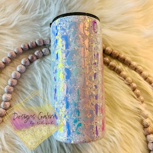 May include: A white tumbler with a holographic leopard print design. The tumbler has a black lid and is filled with iridescent glitter.