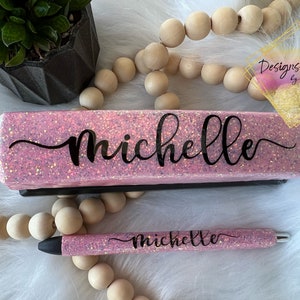 May include: Pink glitter stapler and pen set with the name "Michelle" written in black cursive on both items.