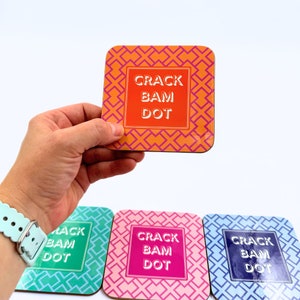 May include: Four square coasters with a geometric pattern in orange, green, pink, and blue. Each coaster has the text "CRACK BAM DOT" in white.