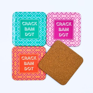 May include: Four square coasters with a geometric pattern in turquoise, pink, and orange. Each coaster features the text "Crack Bam Dot" in white.