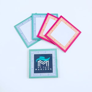 May include: Four blank square cards with a repeating border of the words "MAHJ MAHJ MAHJ" in a teal, orange, pink, and red color scheme. A fifth card with a teal border and the words "MAHJ MAHJ MAHJ" has a logo with the text "MY FAIR MAHJONG" and a stylized hat.