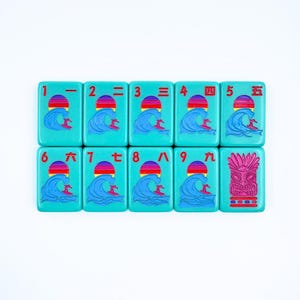 May include: A set of nine turquoise tiles with red and white numbers and Chinese characters. Each tile features a graphic of a surfer riding a wave with a red, orange, and yellow sunset in the background. The last tile features a pink tiki mask.