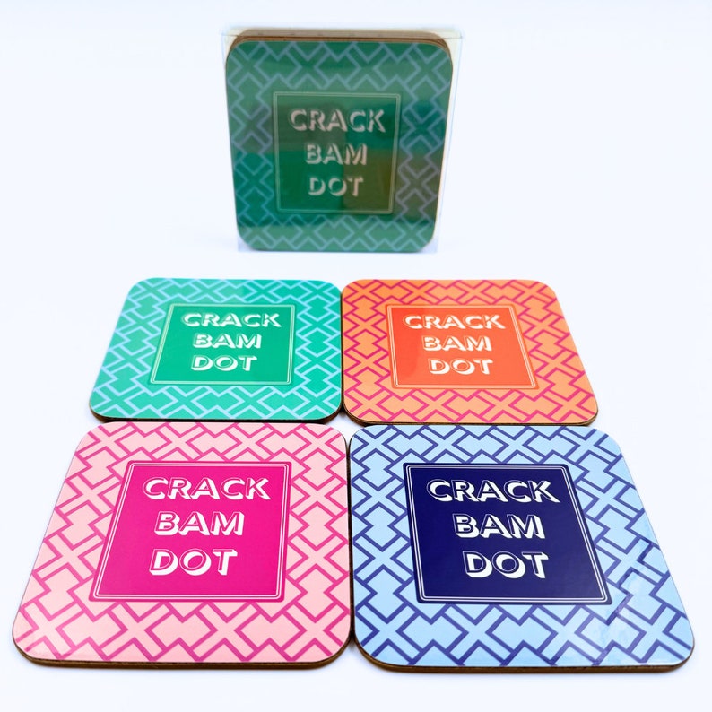 May include: Set of four square coasters with a geometric pattern. Each coaster features the text "CRACK BAM DOT" in a different color: green, orange, pink, and blue.
