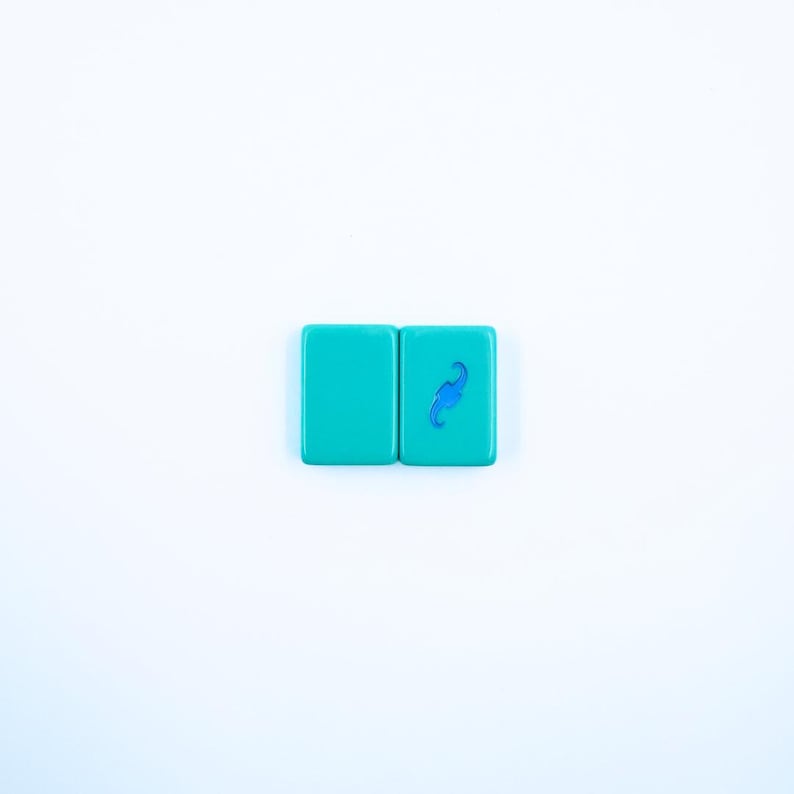 May include: Two turquoise blue square keycaps with a blue swirl design on the right keycap.