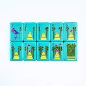 May include: Nine turquoise tiles with white numbers and colorful illustrations. The tiles feature a bird, butterflies, bamboo, and a tiki mask. The tiles are numbered 1 through 9.