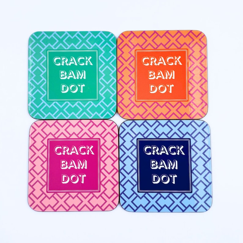 May include: Set of four square coasters with a geometric pattern. Each coaster features the text "CRACK BAM DOT" in white lettering on a different colored background: teal, orange, pink, and blue.