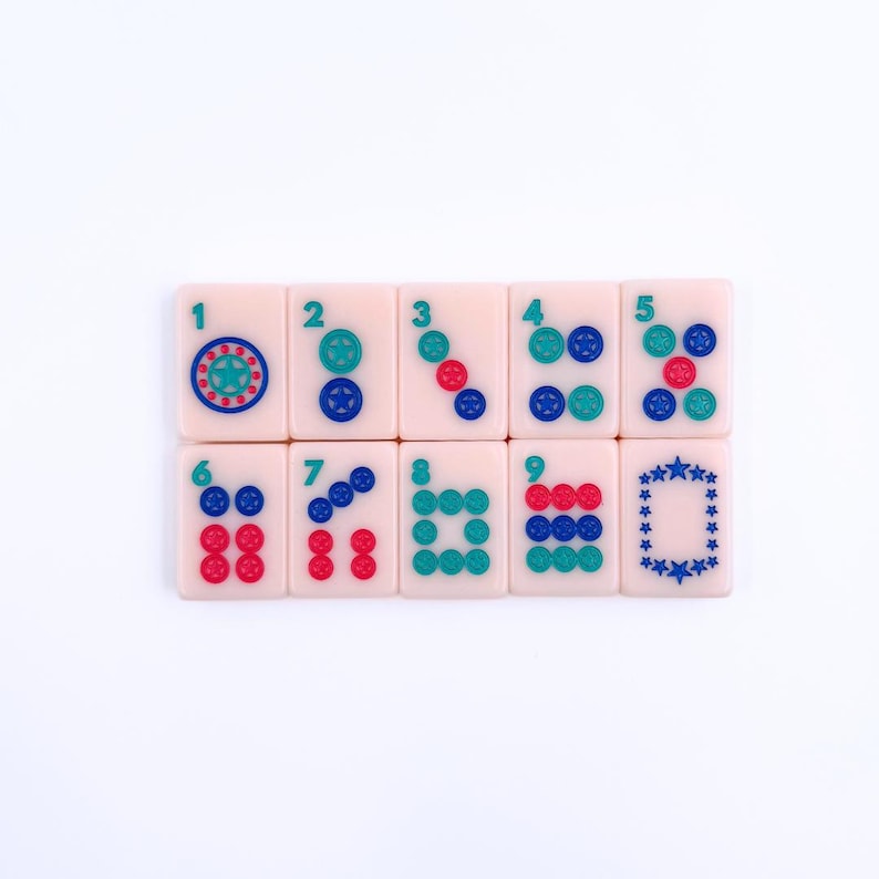 May include: A set of eight pink mahjong tiles with blue and red dots and symbols. The tiles are numbered 1 through 8 and feature a variety of designs, including circles, squares, and stars.
