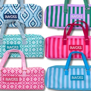 May include: A collection of colorful duffel bags with various patterns and designs. The bags feature geometric and striped patterns in shades of blue, pink, green, and purple. Each bag has a matching handle and the word "RACKS" on the front.