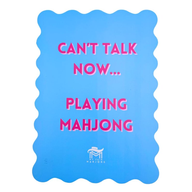 Puede incluir: Una tarjeta azul con un borde ondulado y el texto "Can't talk now... Playing Mahjong" en rosa. La parte inferior de la tarjeta tiene un logotipo para "My Fair Mahjong".
