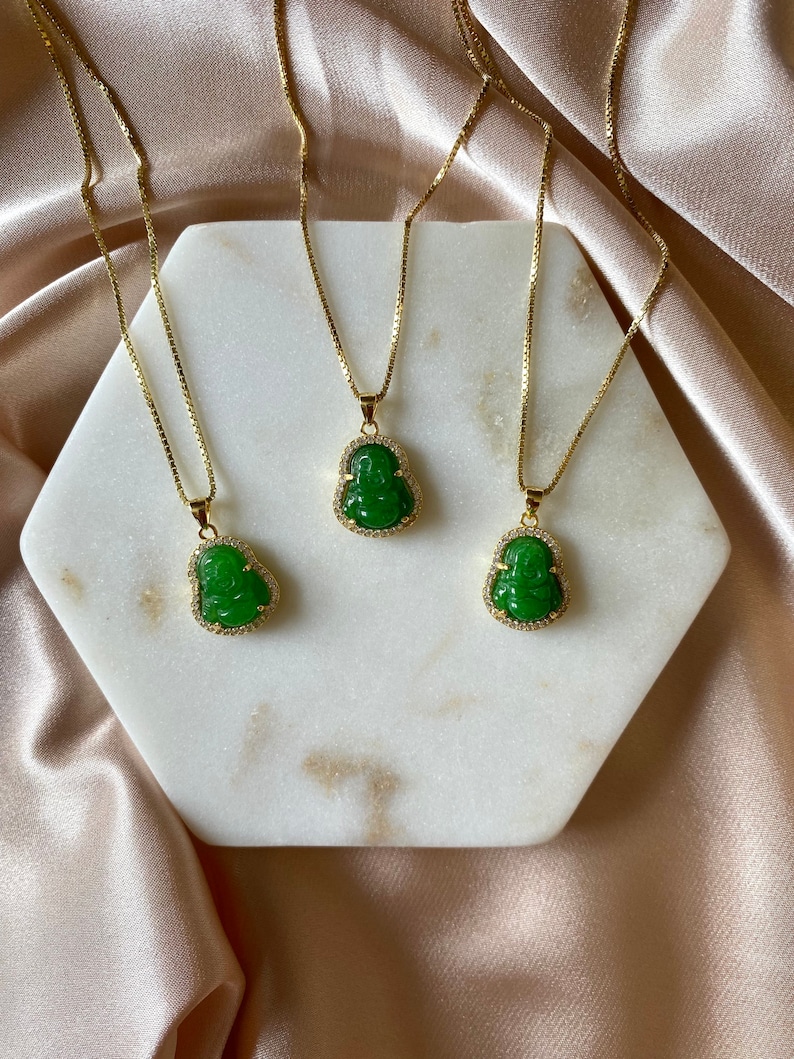 May include: Three gold chains with green jade Buddha pendants. The pendants are detailed with small clear stones.