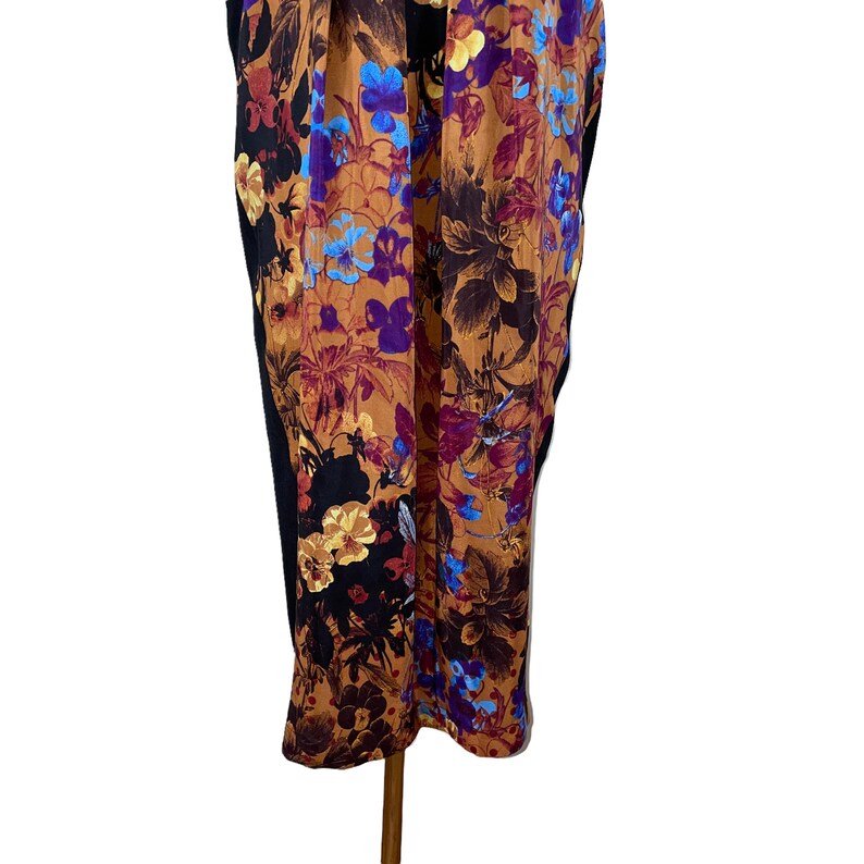 May include: A long, black dress with a floral print in shades of brown, purple, and blue. The dress has a fitted bodice and a flowing skirt.