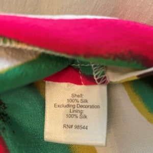 Peut inclure: Une &eacute;tiquette blanche avec du texte noir sur un fond de tissu color&eacute;. L'&eacute;tiquette indique "Shell: 100% Silk Excluding Decoration Lining: 100% Silk RN# 98544".