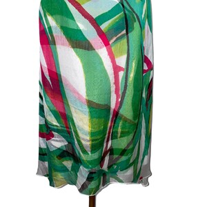 Peut inclure: Un foulard en soie blanc avec un imprim&eacute; abstrait vert, rose et noir. L'imprim&eacute; pr&eacute;sente une vari&eacute;t&eacute; de lignes et de formes, cr&eacute;ant un design moderne et &eacute;l&eacute;gant.