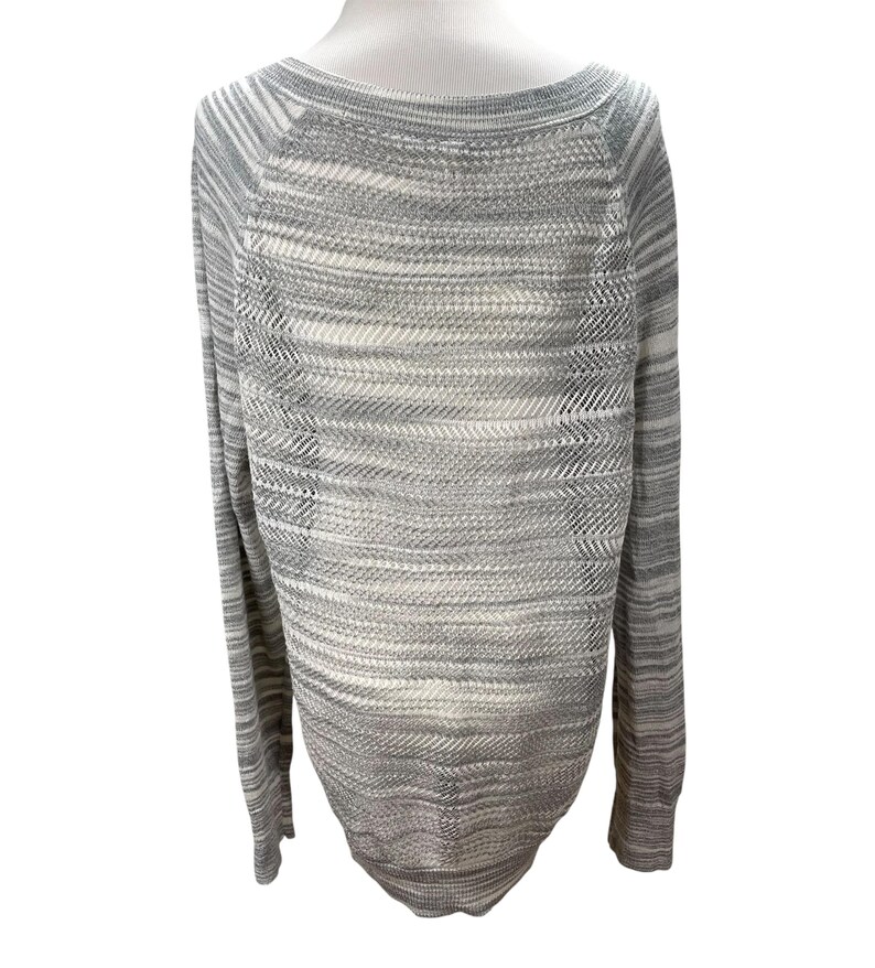 Puede incluir: Un su&eacute;ter de punto gris y blanco con cuello barco y mangas largas. El su&eacute;ter tiene un patr&oacute;n texturizado y se muestra en un maniqu&iacute; blanco. La prenda de punto es de color claro y neutro, adecuada para combinar.