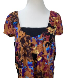 May include: A brown and black floral print short-sleeved top with a black neckline.