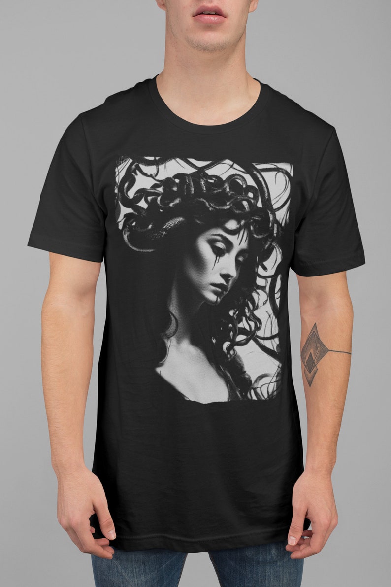 May include: Black t-shirt with a graphic print of a woman with snakes for hair. The woman is looking down and has a sad expression on her face.