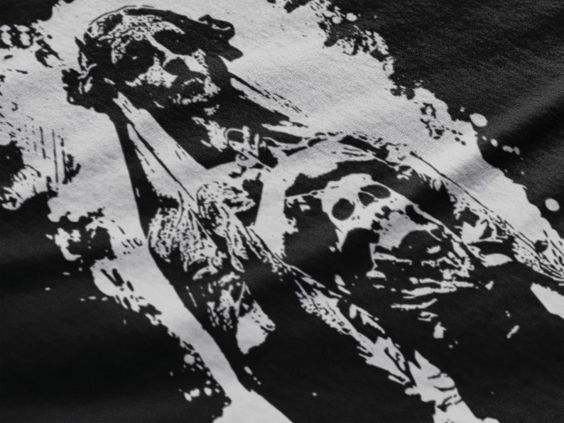 May include: Black and white graphic print of a skull with a bandana on a black t-shirt. The skull is wearing a bandana and has a distressed look.