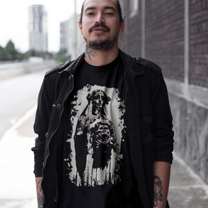 May include: A black t-shirt with a white graphic print of a dog wearing a crown. The dog is standing on a white background with a distressed effect.