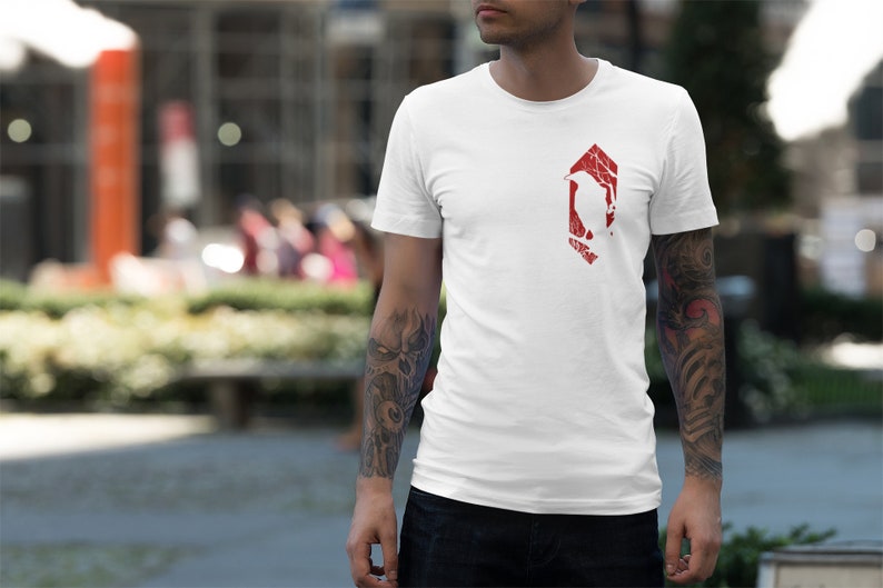 May include: White t-shirt with a red graphic of a bird inside a geometric shape. The graphic has a distressed look.