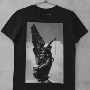 May include: Black and white graphic print of an angel statue holding a sword, printed on a black t-shirt.