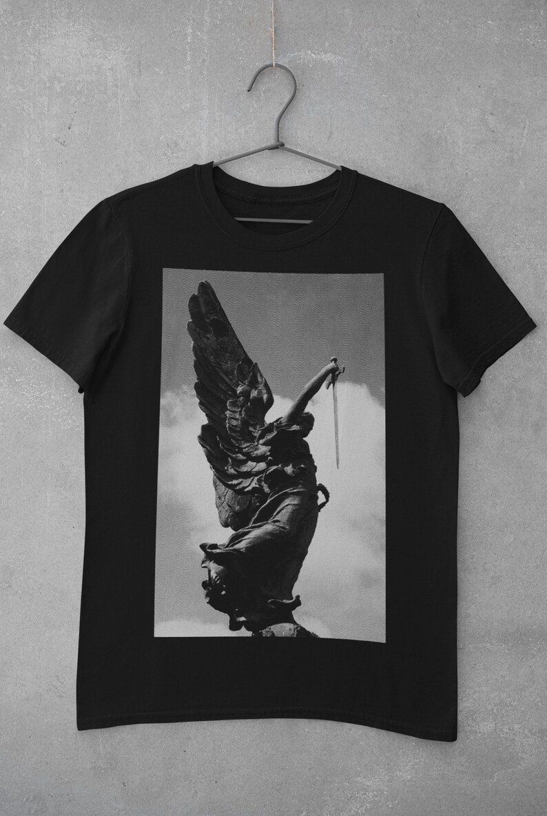 May include: Black and white graphic print of an angel statue holding a sword, printed on a black t-shirt.