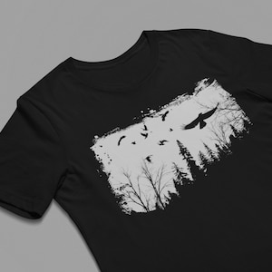 May include: Black t-shirt with a white graphic of a flock of birds flying over a forest silhouette.