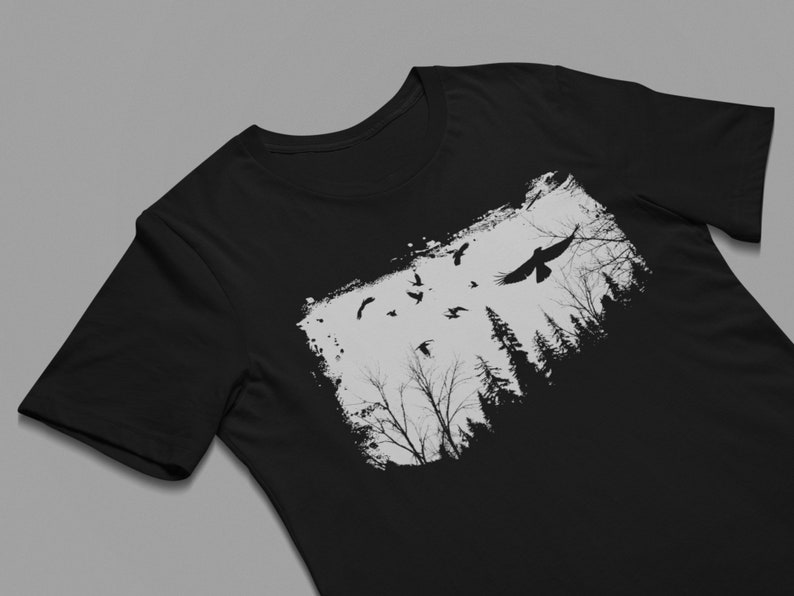 May include: Black t-shirt with a white graphic of a flock of birds flying over a forest silhouette.