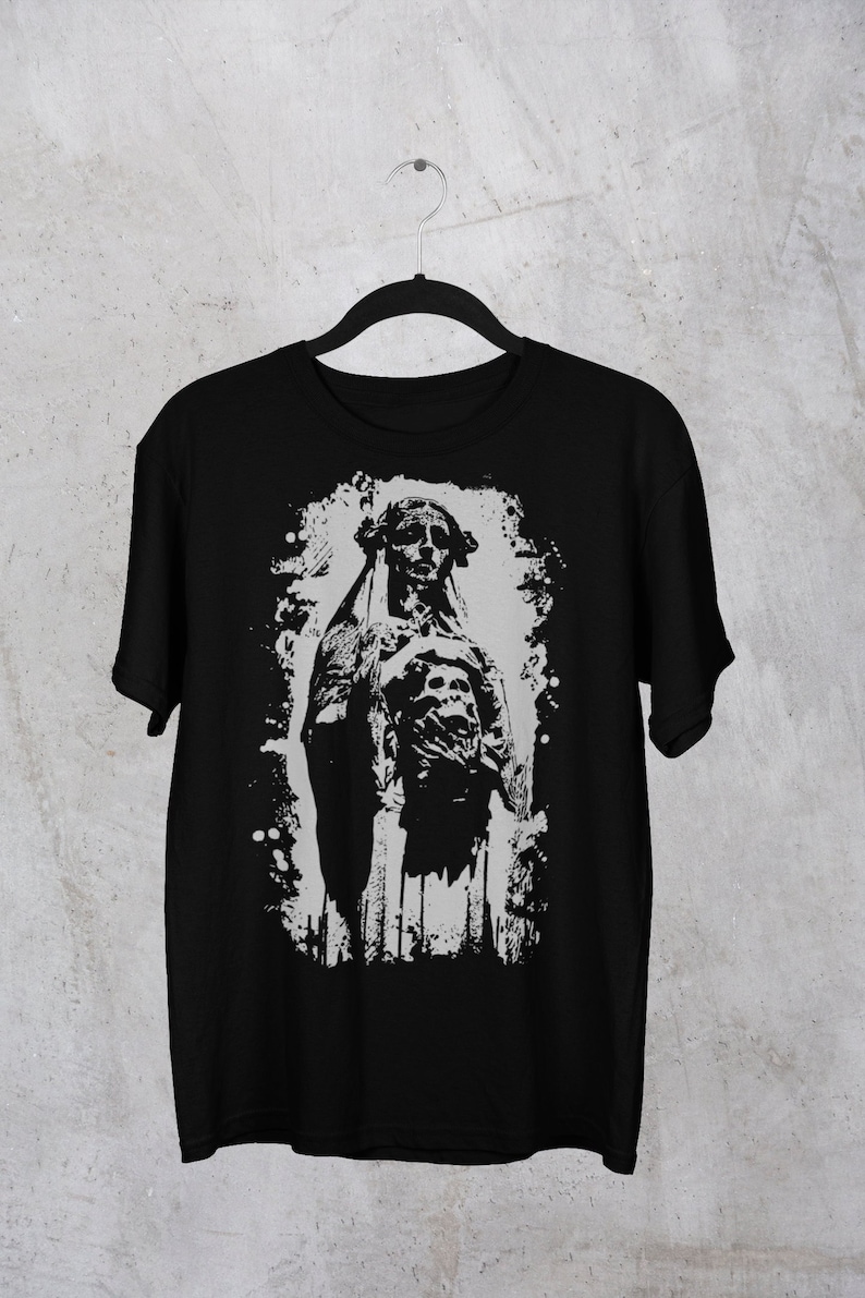 May include: Black t-shirt with a white graphic print of a skeletal figure in a hooded robe. The figure is standing with its arms crossed and has a skull-like face.