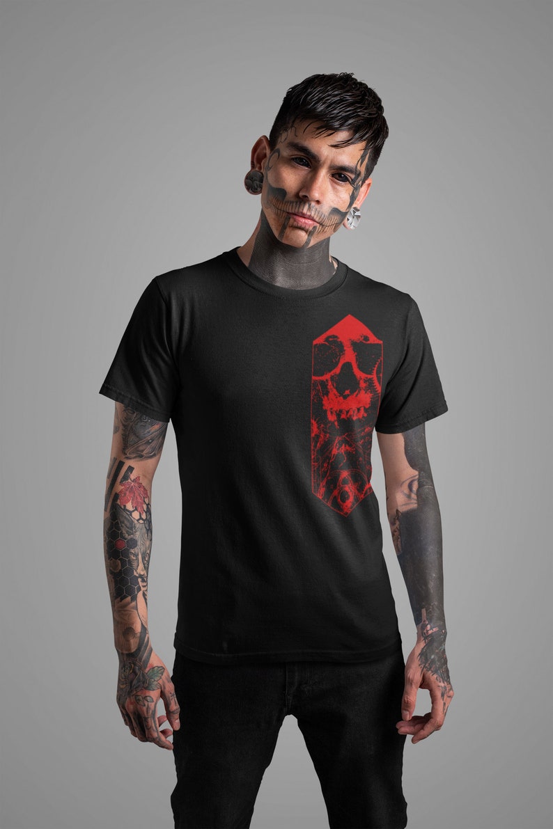 K&ouml;nnte beinhalten: Ein schwarzes T-Shirt mit einem roten Totenkopf-Motiv auf der Vorderseite. Der Totenkopf ist in einer Diamantenform und hat ein detailliertes Design.
