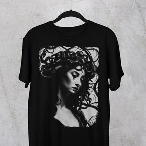 May include: Black t-shirt with a graphic print of a woman with snakes for hair. The image is in black and white.