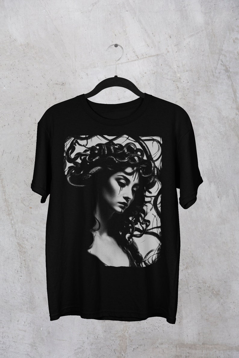 May include: Black t-shirt with a graphic print of a woman with snakes for hair. The image is in black and white.
