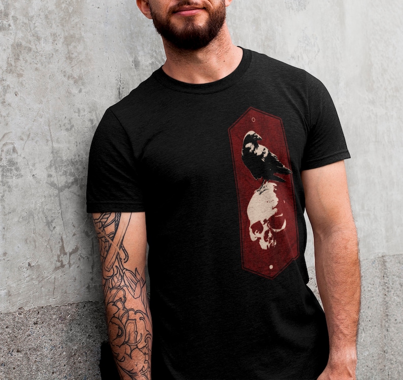 May include: Black t-shirt with a red graphic of a crow perched on a skull.