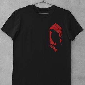 May include: Black t-shirt with a red graphic of a crow perched on a branch in a forest silhouette.