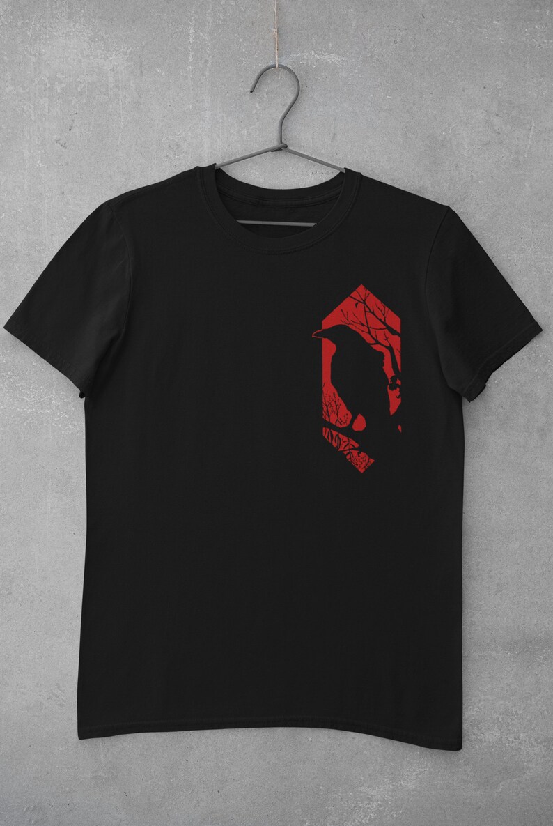May include: Black t-shirt with a red graphic of a crow perched on a branch in a forest silhouette.